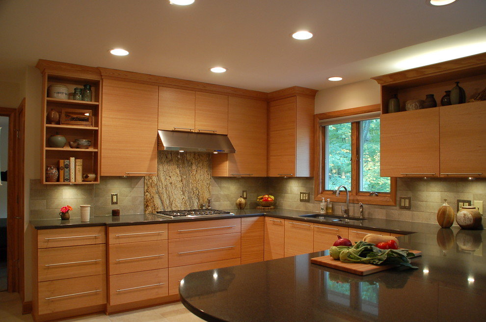Modern inredning av ett mellanstort u-kök, med en undermonterad diskho, släta luckor, skåp i ljust trä, granitbänkskiva, beige stänkskydd, stänkskydd i keramik, rostfria vitvaror och klinkergolv i porslin