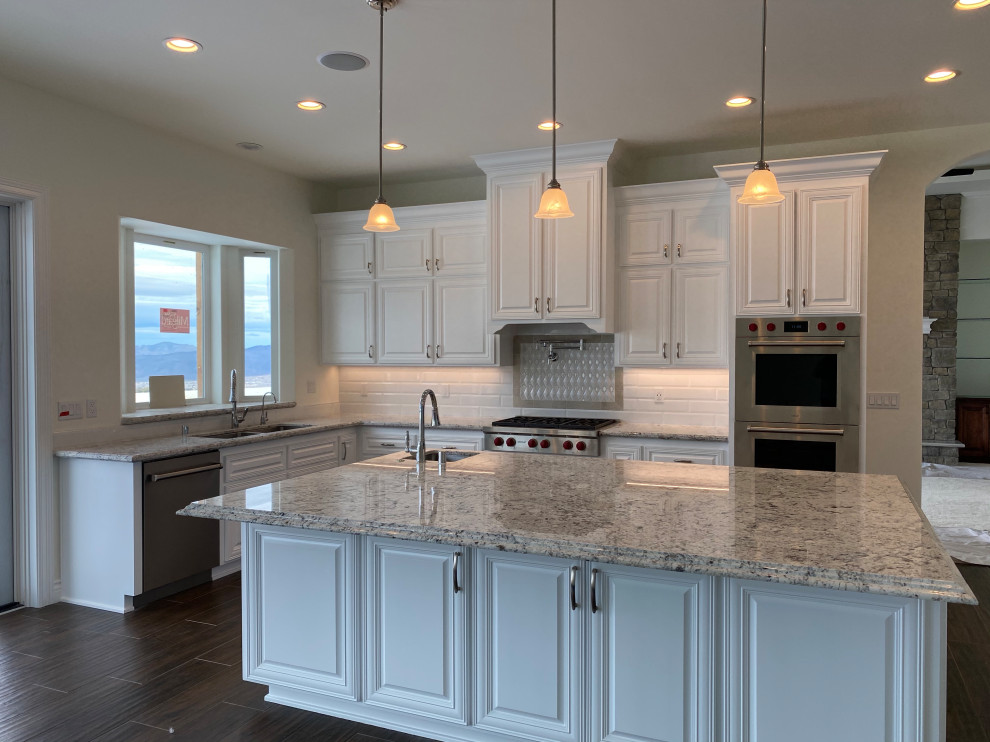 Example of a huge minimalist u-shaped porcelain tile and brown floor open concept kitchen design in Other with an undermount sink, raised-panel cabinets, white cabinets, granite countertops, white backsplash, cement tile backsplash, stainless steel appliances, an island and gray countertops