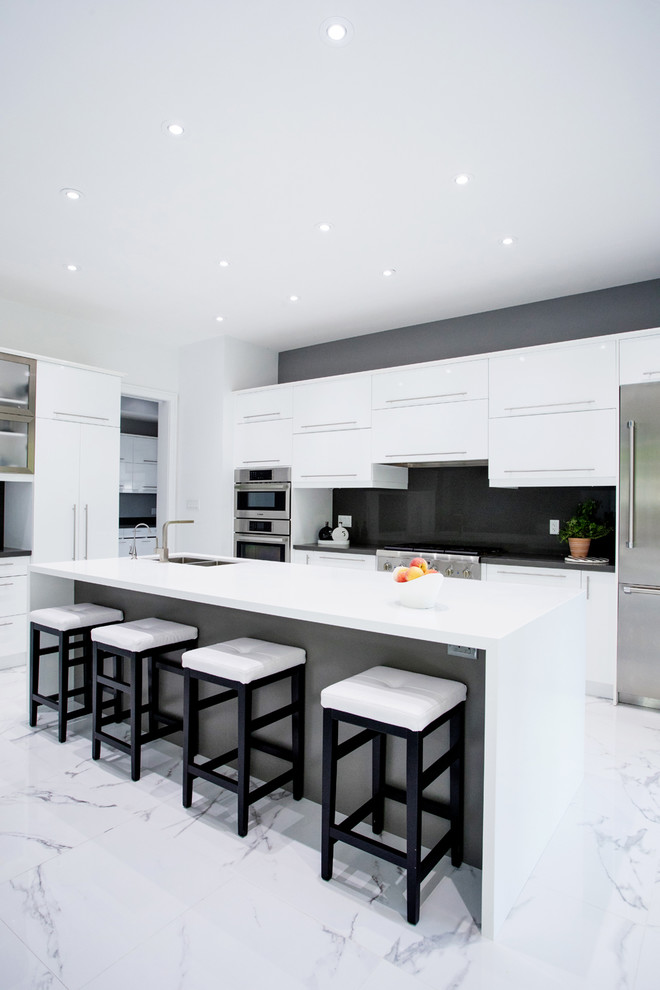 Modern inredning av ett stort vit vitt kök, med en undermonterad diskho, släta luckor, vita skåp, bänkskiva i kvarts, svart stänkskydd, stänkskydd i sten, rostfria vitvaror, marmorgolv, en köksö och vitt golv