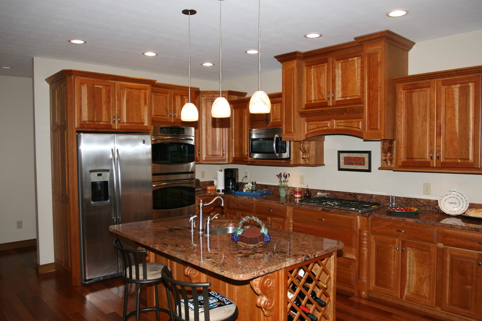 Immagine di una cucina chic di medie dimensioni con ante con bugna sagomata, ante in legno scuro, top in granito, elettrodomestici in acciaio inossidabile e 2 o più isole