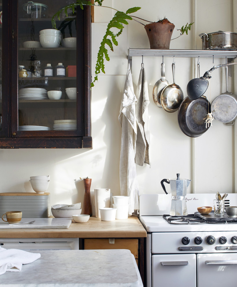 Immagine di un piccolo cucina con isola centrale country con ante di vetro, top in marmo, elettrodomestici bianchi, top bianco, ante in legno bruno e paraspruzzi bianco