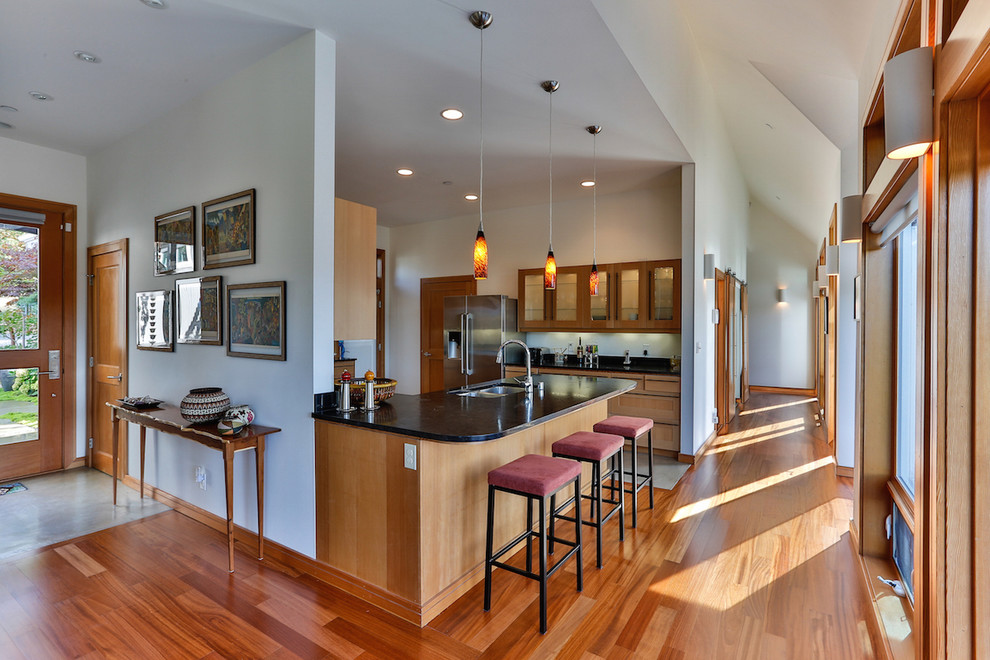 Example of a mid-sized minimalist l-shaped light wood floor and beige floor eat-in kitchen design in Seattle with an undermount sink, shaker cabinets, light wood cabinets, limestone countertops, stainless steel appliances, a peninsula, multicolored backsplash and ceramic backsplash