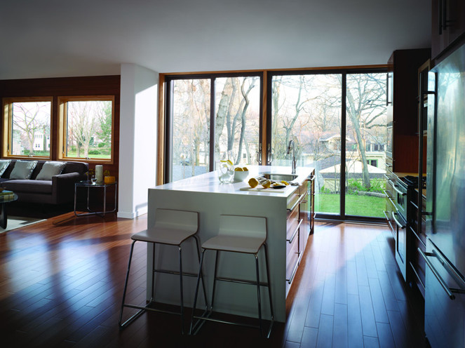 Foto på ett mellanstort funkis linjärt kök med öppen planlösning, med en undermonterad diskho, släta luckor, vita skåp, bänkskiva i kvarts, rostfria vitvaror, vinylgolv och en köksö