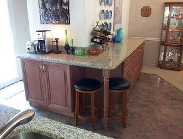 Inspiration for a medium sized l-shaped home bar in St Louis with an integrated sink, raised-panel cabinets, medium wood cabinets, granite worktops, beige splashback, stone slab splashback and ceramic flooring.