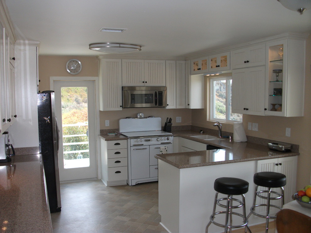 Enclosed kitchen - mid-sized transitional single-wall porcelain tile and beige floor enclosed kitchen idea in San Diego with a double-bowl sink, recessed-panel cabinets, white cabinets, granite countertops, stainless steel appliances and an island