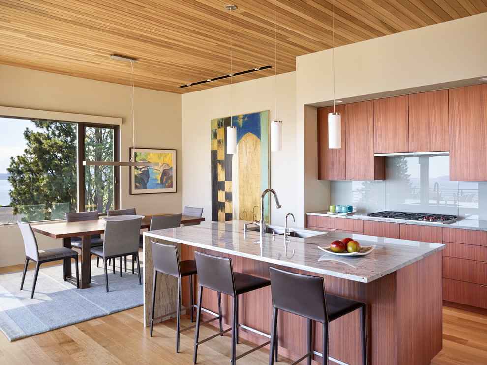 Moderne Küche mit Unterbauwaschbecken, flächenbündigen Schrankfronten, dunklen Holzschränken, Küchenrückwand in Grau, Glasrückwand und braunem Holzboden in Seattle