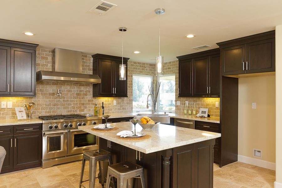 Exempel på ett stort klassiskt u-kök, med en undermonterad diskho, luckor med upphöjd panel, skåp i mörkt trä, bänkskiva i kvarts, brunt stänkskydd, stänkskydd i travertin, rostfria vitvaror, kalkstensgolv, en köksö och beiget golv