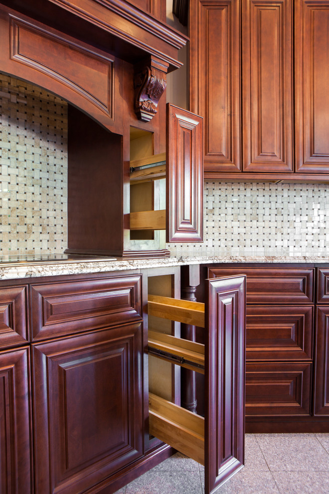 Modelo de cocina tradicional con armarios con paneles con relieve, puertas de armario de madera en tonos medios, encimera de granito, salpicadero beige y salpicadero de azulejos de cerámica