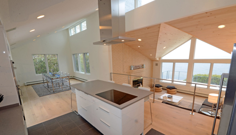 Inspiration for an expansive contemporary galley open plan kitchen in Orange County with flat-panel cabinets, white cabinets, engineered stone countertops, stainless steel appliances, light hardwood flooring and an island.