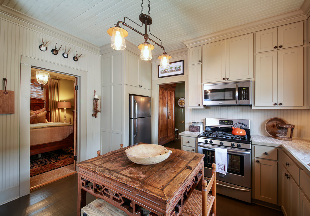 Foto på ett rustikt kök, med skåp i shakerstil, beige skåp, kaklad bänkskiva, beige stänkskydd, rostfria vitvaror, mörkt trägolv och en köksö