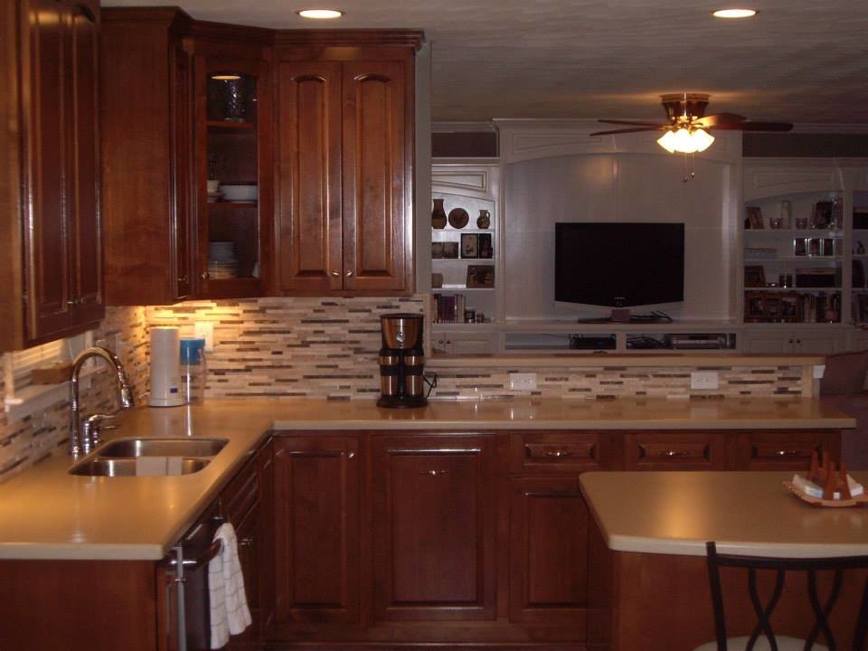 Example of a l-shaped eat-in kitchen design in Other with a drop-in sink, recessed-panel cabinets, medium tone wood cabinets, laminate countertops, multicolored backsplash, matchstick tile backsplash, stainless steel appliances and an island