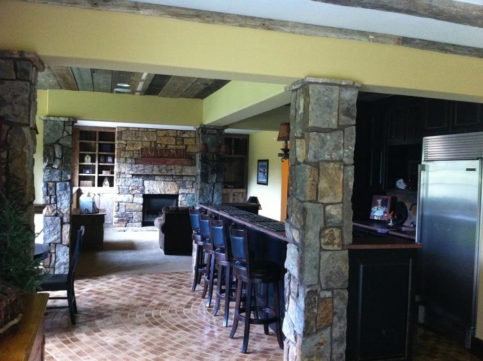 Foto på ett litet rustikt brun kök, med skåp i mörkt trä, träbänkskiva, rostfria vitvaror, tegelgolv, en köksö och brunt golv