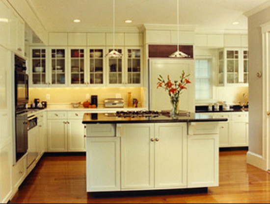 Mid-sized l-shaped light wood floor enclosed kitchen photo in Boston with an undermount sink, shaker cabinets, white cabinets, granite countertops, yellow backsplash, black appliances and an island