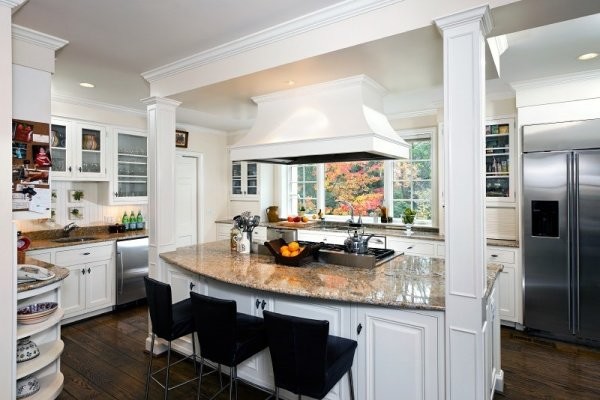 Foto på ett mellanstort vintage kök, med en dubbel diskho, luckor med upphöjd panel, vita skåp, bänkskiva i täljsten, vitt stänkskydd, stänkskydd i sten, rostfria vitvaror, mörkt trägolv och en köksö