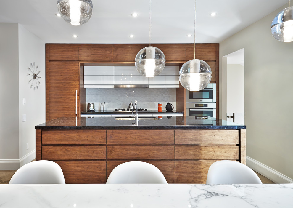 Inspiration for a modern galley eat-in kitchen remodel in Toronto with an undermount sink, flat-panel cabinets, dark wood cabinets, marble countertops, white backsplash and paneled appliances