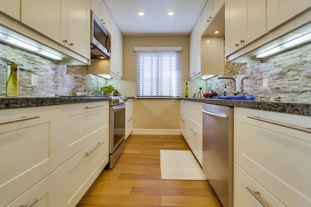 Photo of a medium sized classic galley enclosed kitchen in Los Angeles with a submerged sink, shaker cabinets, white cabinets, granite worktops, multi-coloured splashback, stainless steel appliances, matchstick tiled splashback, medium hardwood flooring and no island.