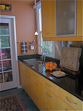 Photo of a contemporary galley enclosed kitchen in San Francisco with a submerged sink, shaker cabinets, light wood cabinets, granite worktops, metallic splashback, metal splashback and black appliances.