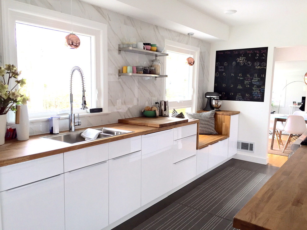 Idée de décoration pour une cuisine parallèle et encastrable minimaliste de taille moyenne avec un placard à porte plane, des portes de placard blanches et un plan de travail en bois.