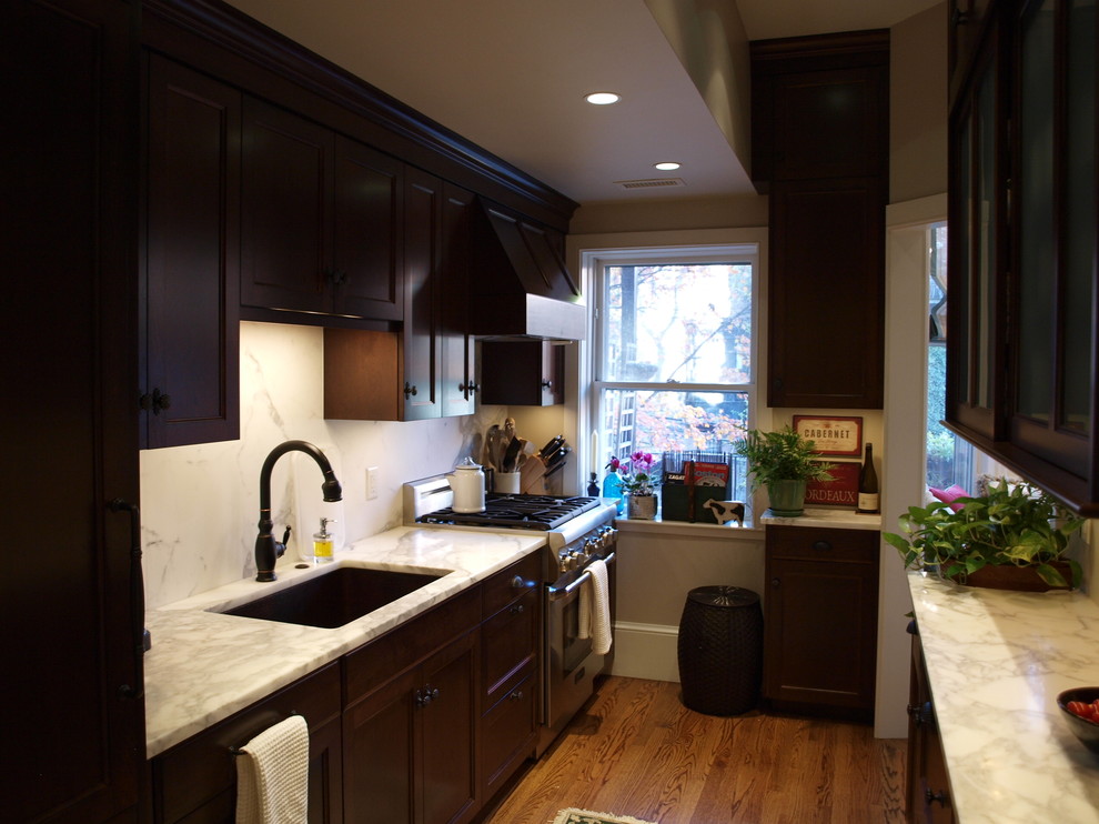 This is an example of a medium sized traditional galley enclosed kitchen in Boston with a submerged sink, recessed-panel cabinets, dark wood cabinets, quartz worktops, stainless steel appliances, dark hardwood flooring and no island.