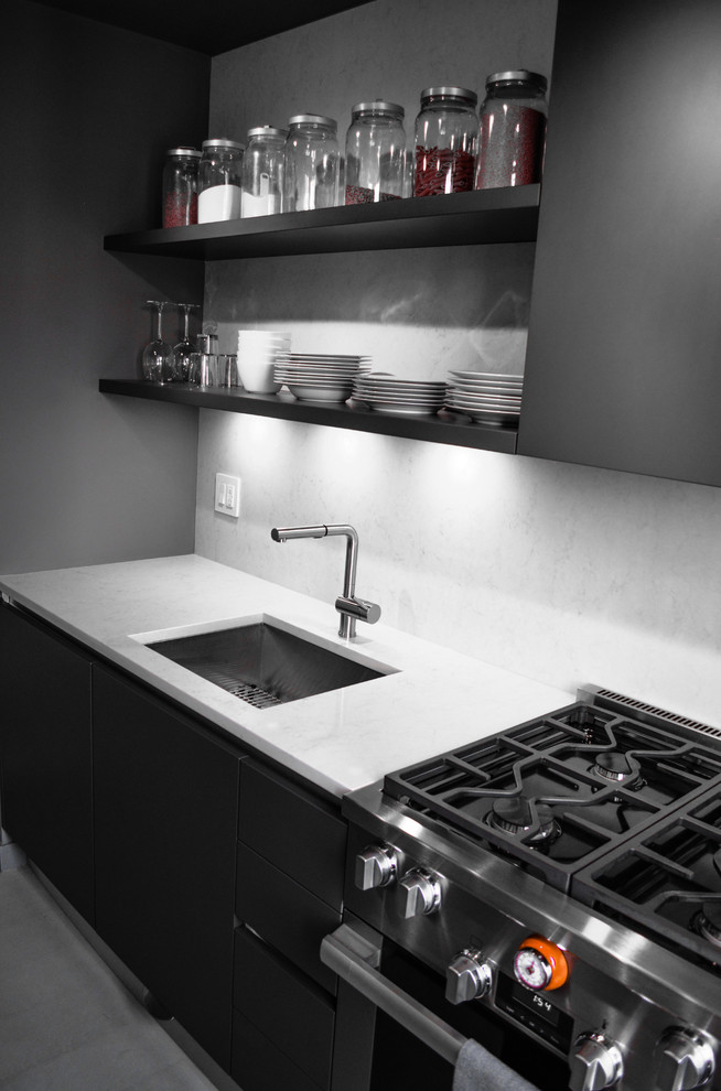 Foto di una cucina parallela contemporanea di medie dimensioni con lavello sottopiano, ante lisce, ante nere, top in quarzo composito, paraspruzzi grigio, elettrodomestici in acciaio inossidabile e pavimento grigio