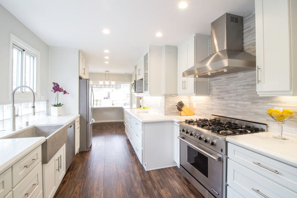 Inspiration for a large contemporary galley enclosed kitchen in Los Angeles with a belfast sink, shaker cabinets, white cabinets, engineered stone countertops, grey splashback, glass tiled splashback, stainless steel appliances, ceramic flooring and no island.