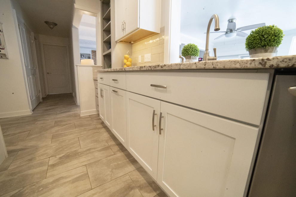 Foto på ett mellanstort vintage flerfärgad kök, med en undermonterad diskho, luckor med infälld panel, vita skåp, granitbänkskiva, beige stänkskydd, stänkskydd i keramik, rostfria vitvaror, klinkergolv i keramik, en köksö och grått golv