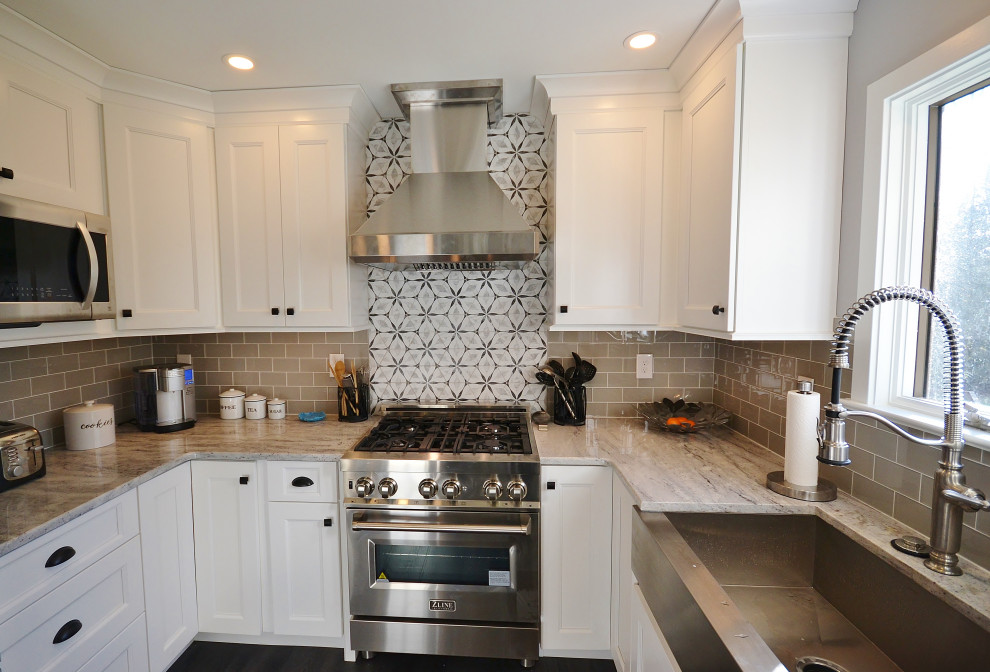 This is an example of a medium sized classic l-shaped kitchen/diner in Philadelphia with a belfast sink, raised-panel cabinets, white cabinets, granite worktops, beige splashback, metro tiled splashback, stainless steel appliances, vinyl flooring, a breakfast bar, brown floors and beige worktops.