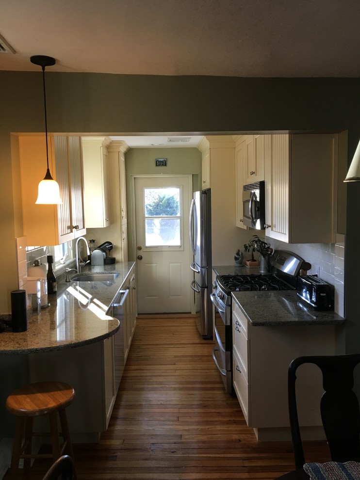 Enclosed kitchen - small transitional galley light wood floor enclosed kitchen idea in Philadelphia with an undermount sink, flat-panel cabinets, yellow cabinets, quartz countertops, white backsplash, ceramic backsplash, stainless steel appliances and no island