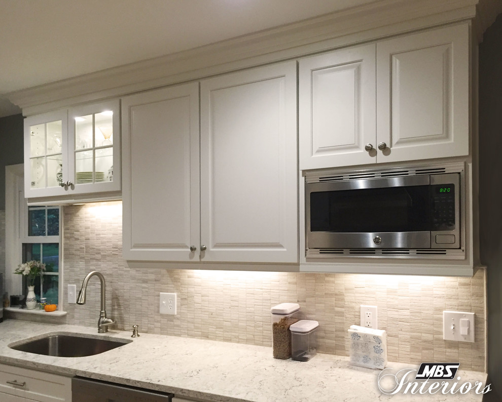 Medium sized traditional grey and cream galley kitchen/diner in Cleveland with a submerged sink, white cabinets, engineered stone countertops, grey splashback, metro tiled splashback, stainless steel appliances, a breakfast bar, raised-panel cabinets, light hardwood flooring and brown floors.