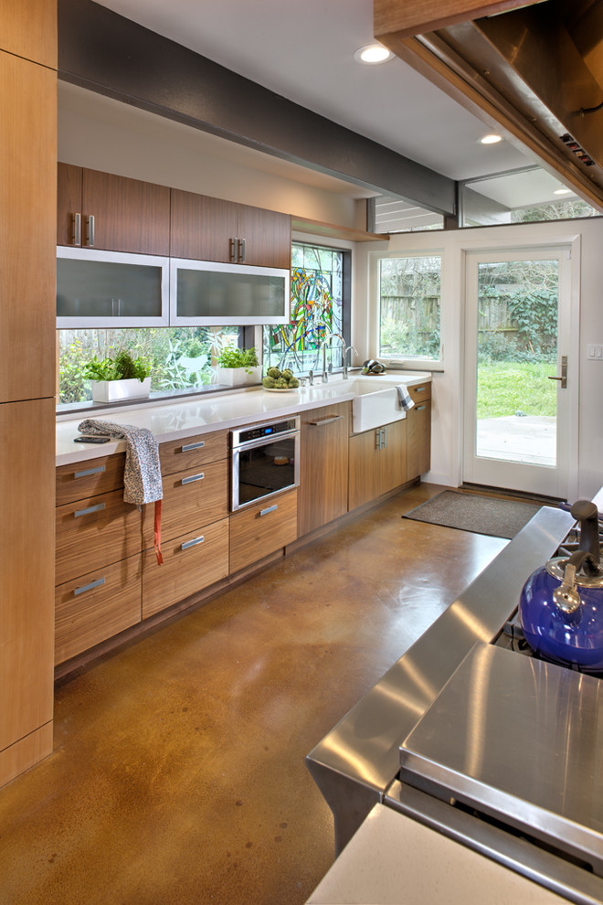 Inspiration for a mid-sized modern galley concrete floor eat-in kitchen remodel in Sacramento with a farmhouse sink, glass-front cabinets, medium tone wood cabinets, quartz countertops, stainless steel appliances and an island