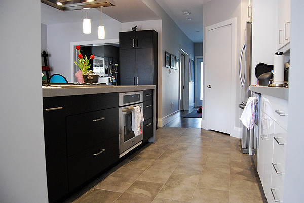 This is an example of a small contemporary galley kitchen/diner in Toronto with flat-panel cabinets, white cabinets, concrete worktops, metallic splashback, porcelain splashback and an island.