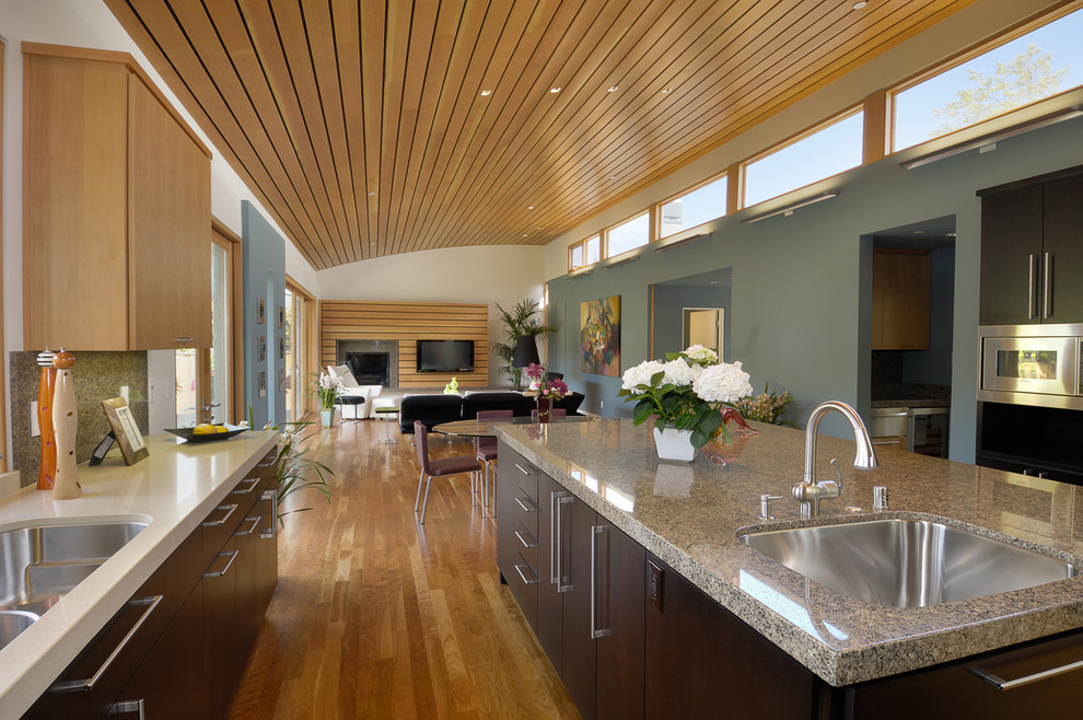 На фото: кухня-гостиная в современном стиле с врезной мойкой, плоскими фасадами и темными деревянными фасадами с