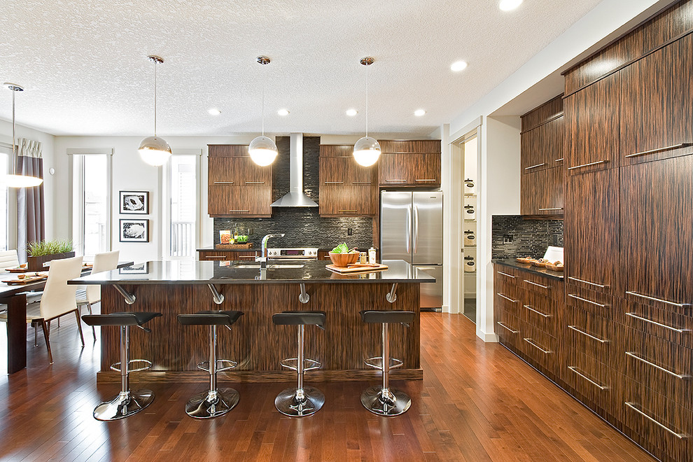 Immagine di una cucina design con ante lisce, ante in legno bruno, paraspruzzi nero e elettrodomestici in acciaio inossidabile