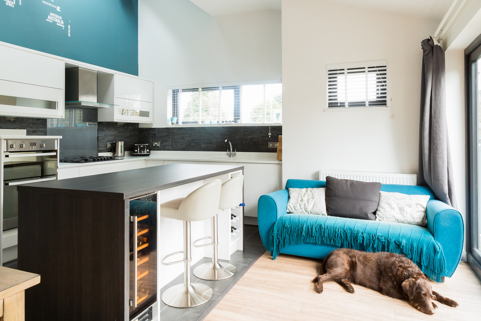 Medium sized contemporary l-shaped open plan kitchen in Other with a submerged sink, flat-panel cabinets, white cabinets, quartz worktops, grey splashback, glass sheet splashback, stainless steel appliances, lino flooring and an island.