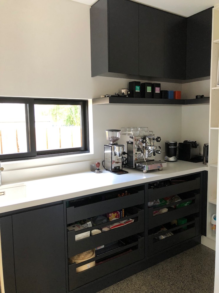 Example of a mid-sized galley concrete floor and gray floor open concept kitchen design in Sydney with an undermount sink, flat-panel cabinets, black cabinets, quartz countertops, mirror backsplash, stainless steel appliances, an island and white countertops