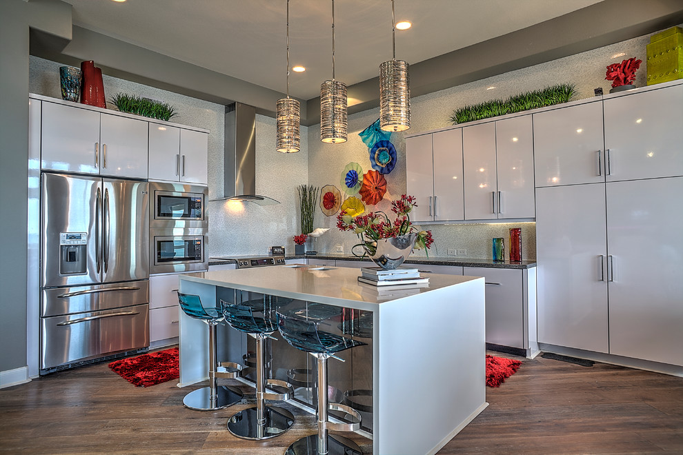 Photo of a contemporary l-shaped open plan kitchen in Houston with an island, a submerged sink, flat-panel cabinets, white cabinets, engineered stone countertops, white splashback, ceramic splashback, stainless steel appliances and porcelain flooring.