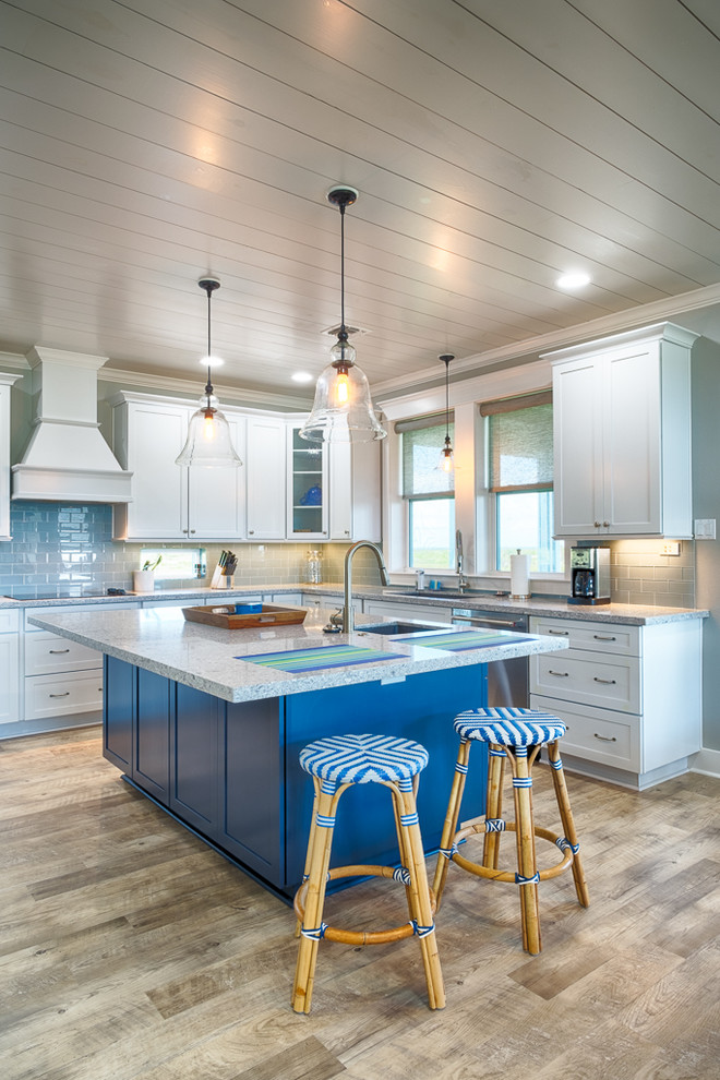 Idée de décoration pour une cuisine marine en L avec un évier encastré, un placard à porte shaker, des portes de placard blanches, une crédence bleue, une crédence en carrelage métro, parquet clair, îlot, un sol beige et fenêtre au-dessus de l'évier.