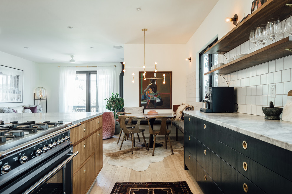 This is an example of a large bohemian l-shaped open plan kitchen in Salt Lake City with a built-in sink, flat-panel cabinets, green cabinets, marble worktops, white splashback, ceramic splashback, coloured appliances, light hardwood flooring and an island.