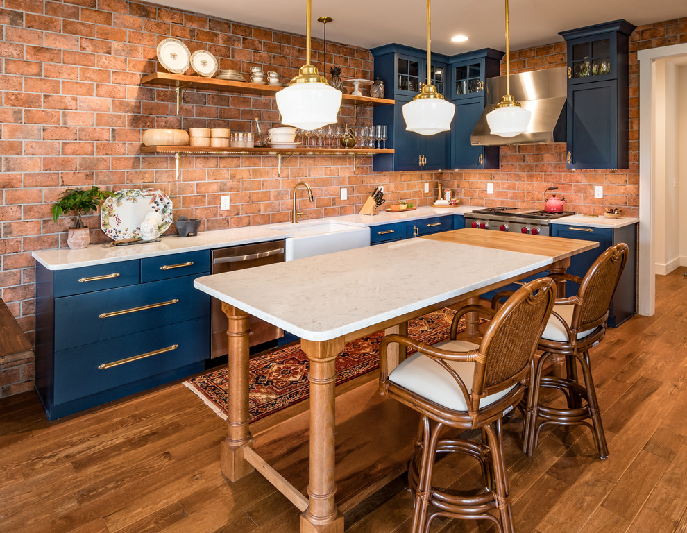 Stilmix Küche mit Landhausspüle, Schrankfronten im Shaker-Stil, blauen Schränken, Quarzit-Arbeitsplatte, braunem Holzboden und Kücheninsel in Grand Rapids