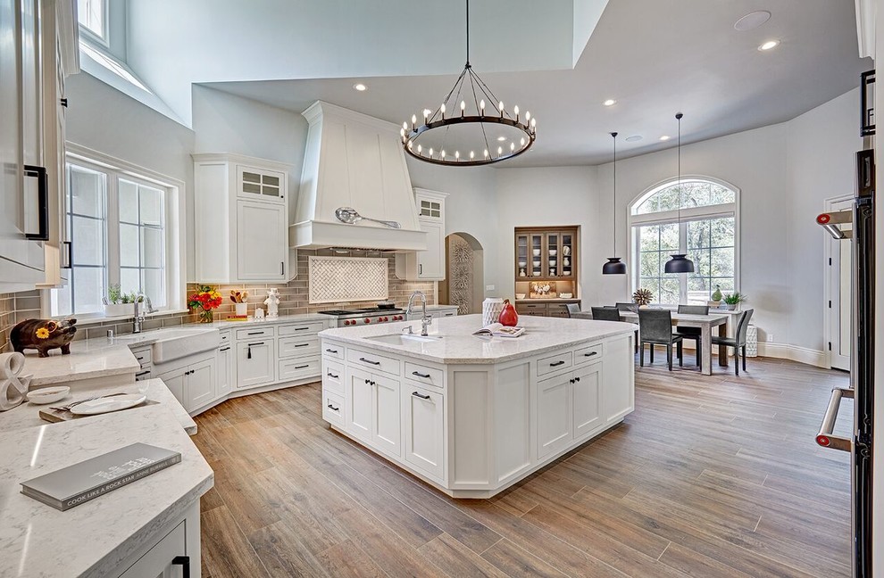 Design ideas for a large classic u-shaped enclosed kitchen in Sacramento with a belfast sink, shaker cabinets, white cabinets, marble worktops, brown splashback, metro tiled splashback, stainless steel appliances, dark hardwood flooring, an island and brown floors.