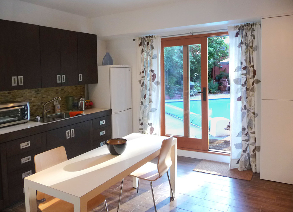 Immagine di una cucina abitabile minimal con lavello da incasso, ante in legno bruno, paraspruzzi multicolore e elettrodomestici bianchi