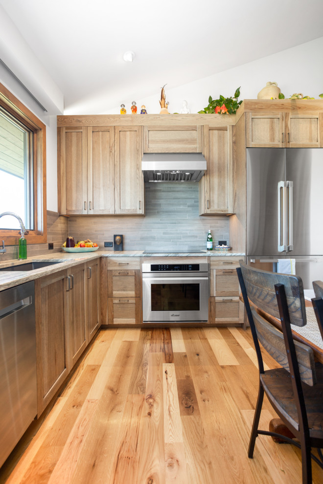 Stilmix Küche mit Waschbecken, hellen Holzschränken, Granit-Arbeitsplatte, Küchengeräten aus Edelstahl, hellem Holzboden und grauer Arbeitsplatte in Salt Lake City