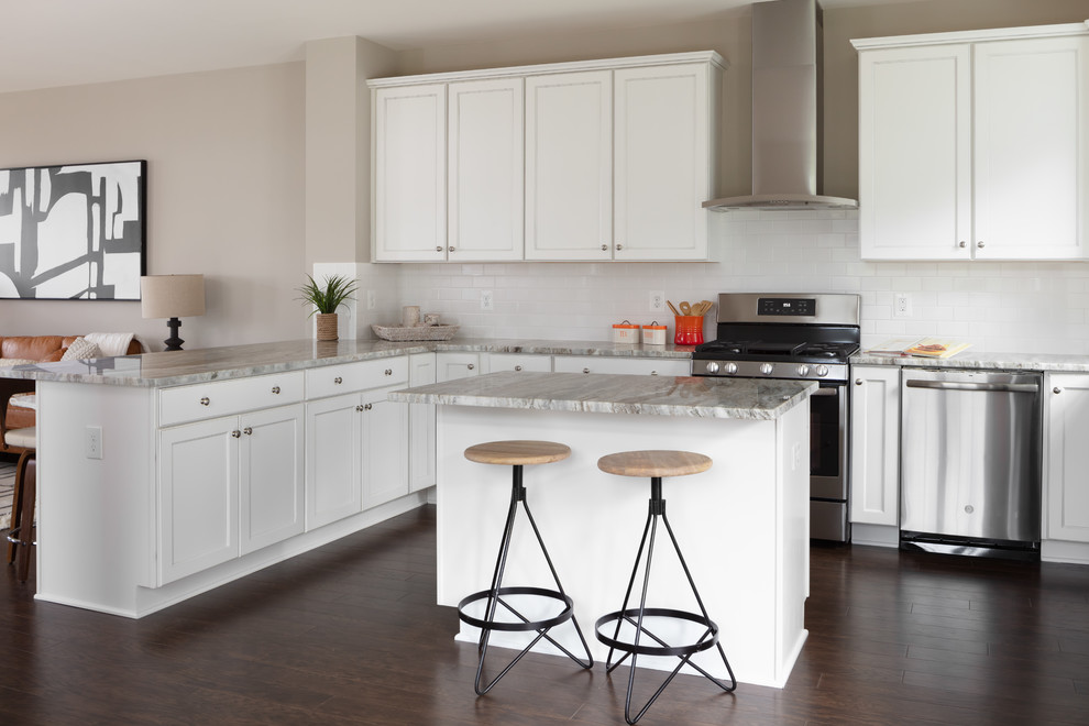 Mid-sized transitional u-shaped laminate floor and brown floor open concept kitchen photo in Other with an undermount sink, recessed-panel cabinets, white cabinets, granite countertops, white backsplash, subway tile backsplash, stainless steel appliances, an island and beige countertops