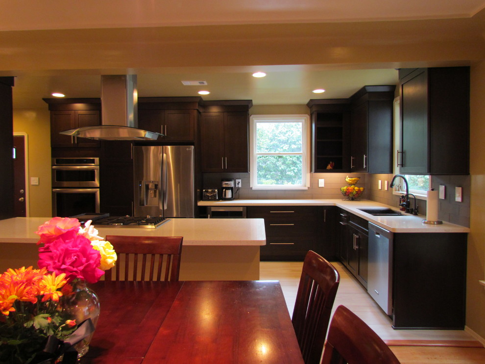 Exemple d'une cuisine chic en bois foncé avec un placard à porte shaker, un plan de travail en quartz modifié, une crédence grise, une crédence en carreau de verre et un électroménager en acier inoxydable.