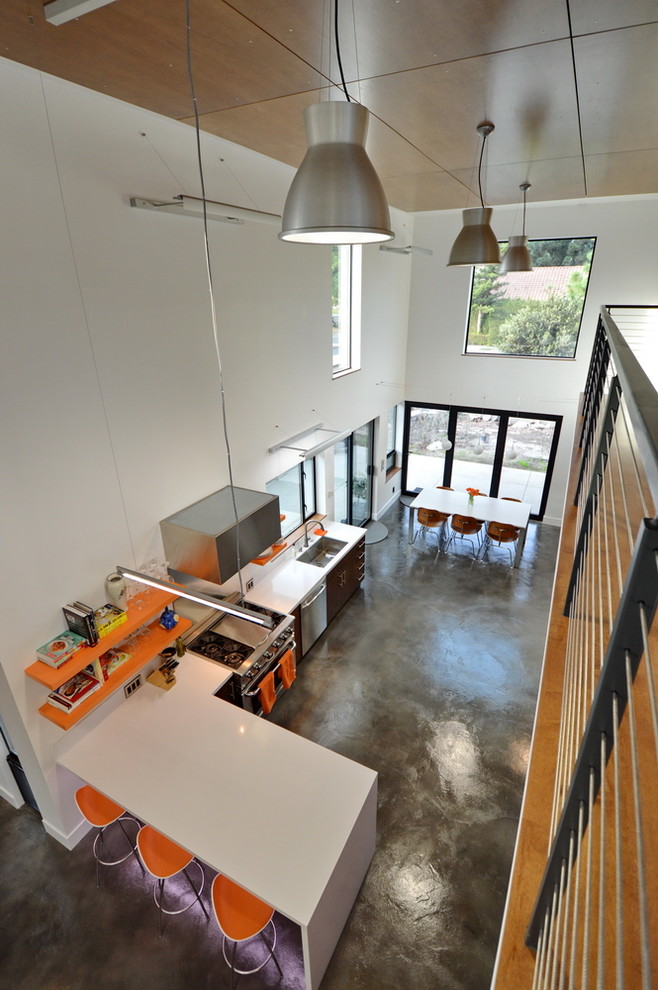 Mid-sized minimalist l-shaped concrete floor open concept kitchen photo in Orange County with an undermount sink, flat-panel cabinets, dark wood cabinets, solid surface countertops, stainless steel appliances and a peninsula