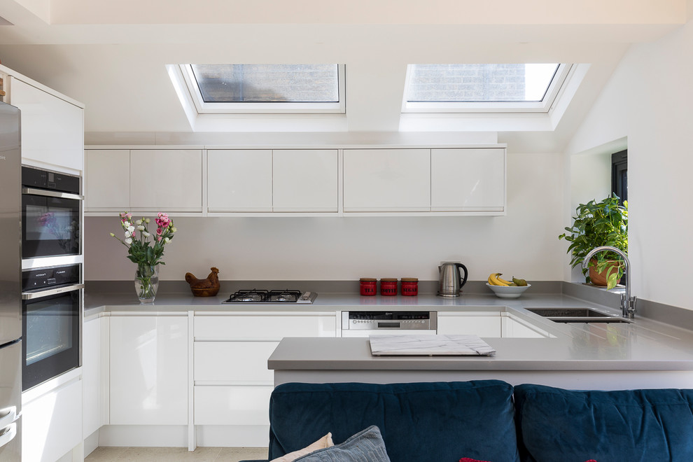 Modern inredning av ett litet kök, med en undermonterad diskho, släta luckor, vita skåp, bänkskiva i koppar, rostfria vitvaror, klinkergolv i porslin och beiget golv