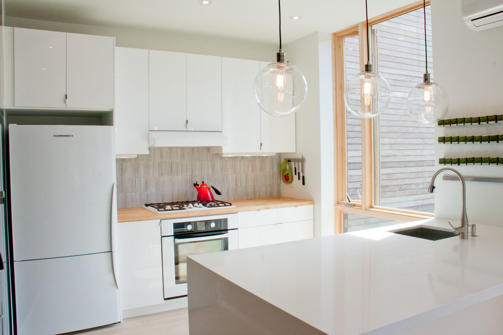 Contemporary galley enclosed kitchen in Toronto with flat-panel cabinets, white cabinets, engineered stone countertops, a single-bowl sink and multi-coloured splashback.