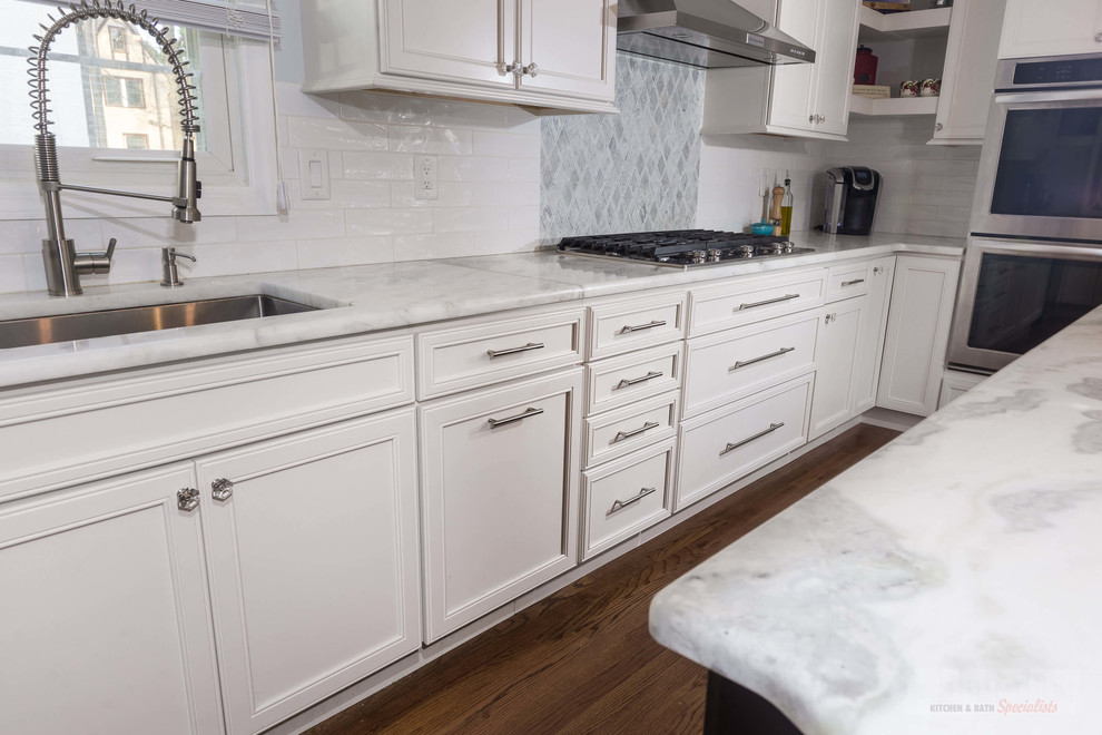 ニューヨークにある高級な広いおしゃれなキッチン (アンダーカウンターシンク、フラットパネル扉のキャビネット、白いキャビネット、珪岩カウンター、白いキッチンパネル、磁器タイルのキッチンパネル、シルバーの調理設備、合板フローリング) の写真