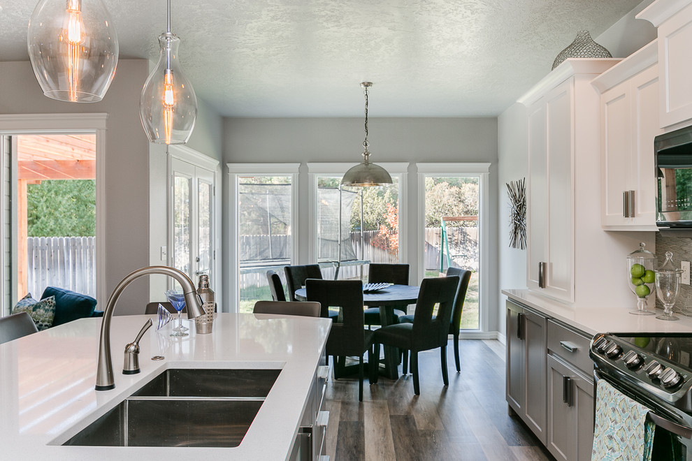 This is an example of a medium sized classic single-wall kitchen/diner in Boise with a double-bowl sink, shaker cabinets, white cabinets, engineered stone countertops, grey splashback, glass tiled splashback, stainless steel appliances, vinyl flooring, an island, grey floors and white worktops.