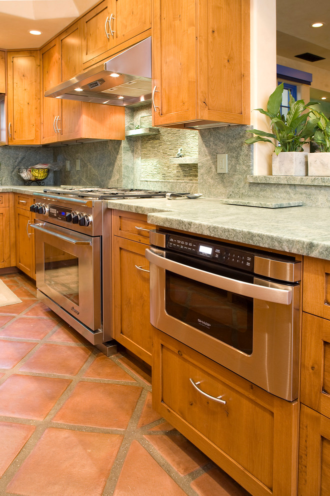 Eclectic galley enclosed kitchen in Santa Barbara with an integrated sink, shaker cabinets, medium wood cabinets, granite worktops, green splashback, stone tiled splashback, integrated appliances and terracotta flooring.